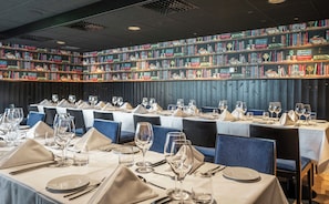 A dining area with tables set for a meal, each with wine glasses and cutlery.