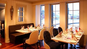 Un restaurante con interior de madera, ventanas grandes, una banca y mesas dispuestas para comer.