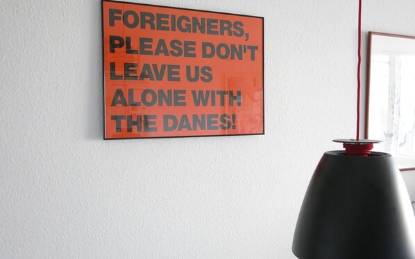 A wall with a sign that reads "FOREIGNERS, PLEASE DON'T LEAVE US ALONE WITH THE DANES!"