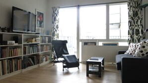 Una sala de estar con una estantería, un sillón de cuero negro, una mesita y un sofá.