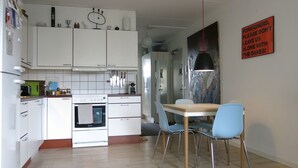 Una cocina moderna con armarios blancos, una estufa y un comedor con mesa y sillas.