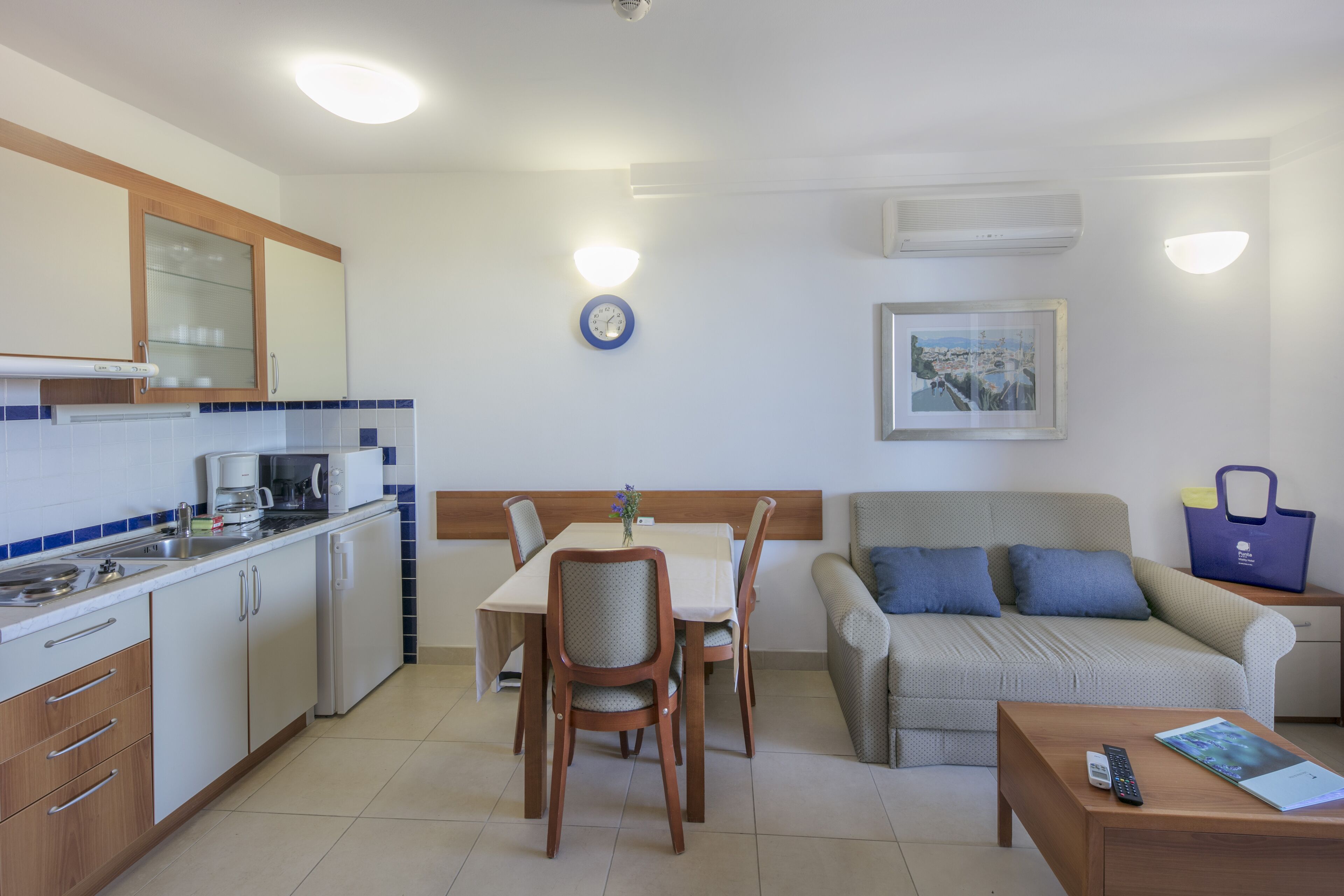 A compact kitchen with a dining area, a sofa, and a small table.