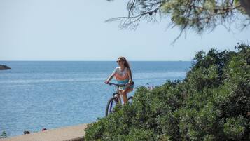 A person riding a bicycle on a coastal path with a view of the sea.
