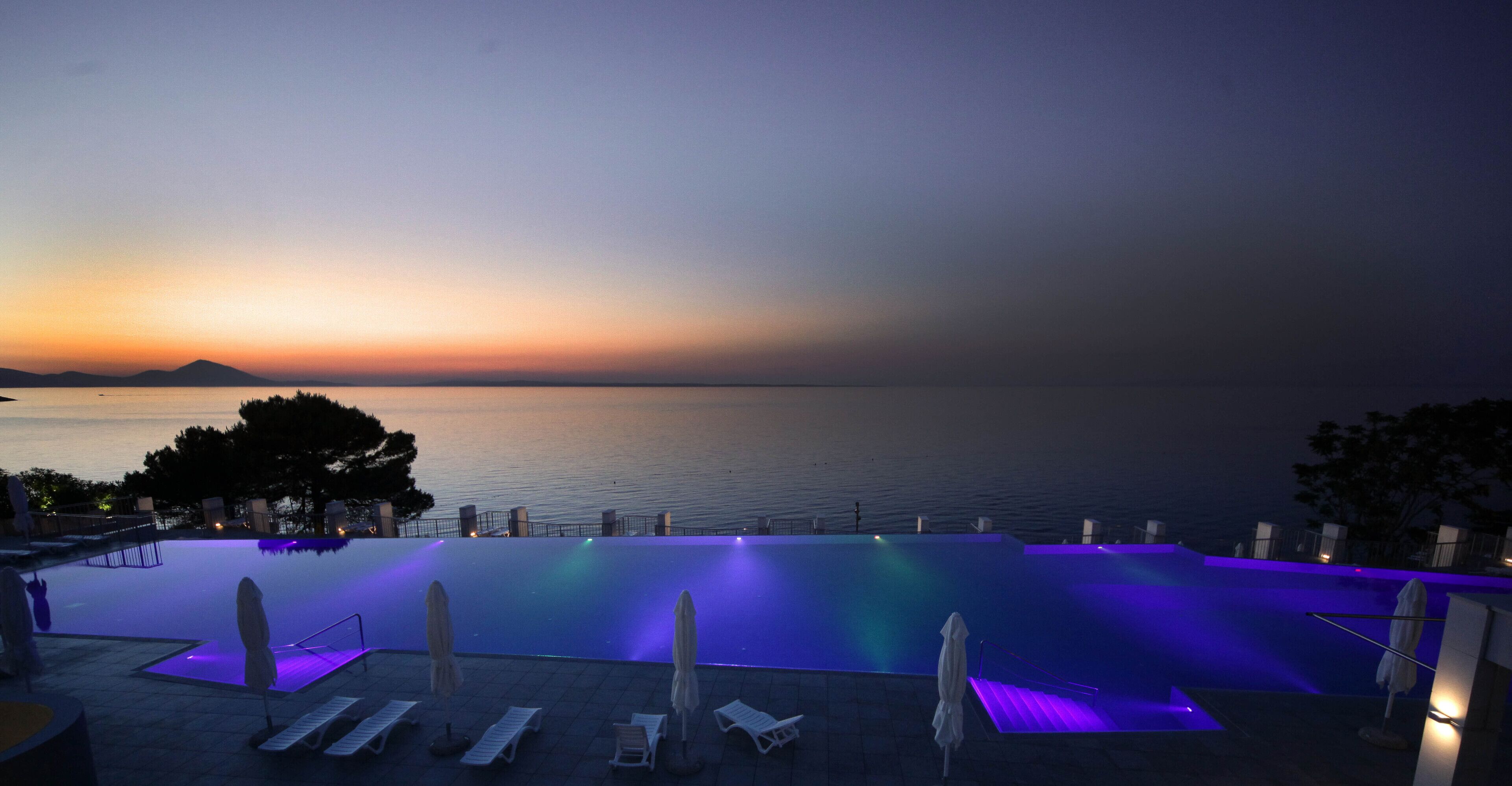 Una piscina infinita con vistas al mar al atardecer.