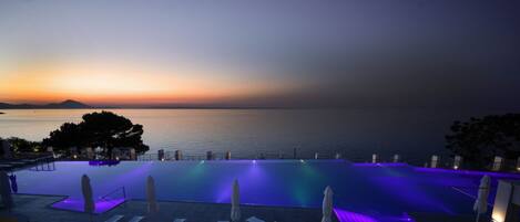 Una piscina infinita con vistas al mar al atardecer.