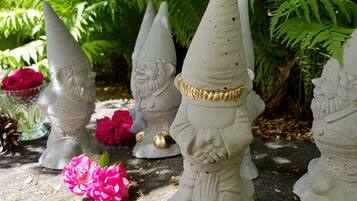 Garden gnomes and a pink flower on a stone surface.