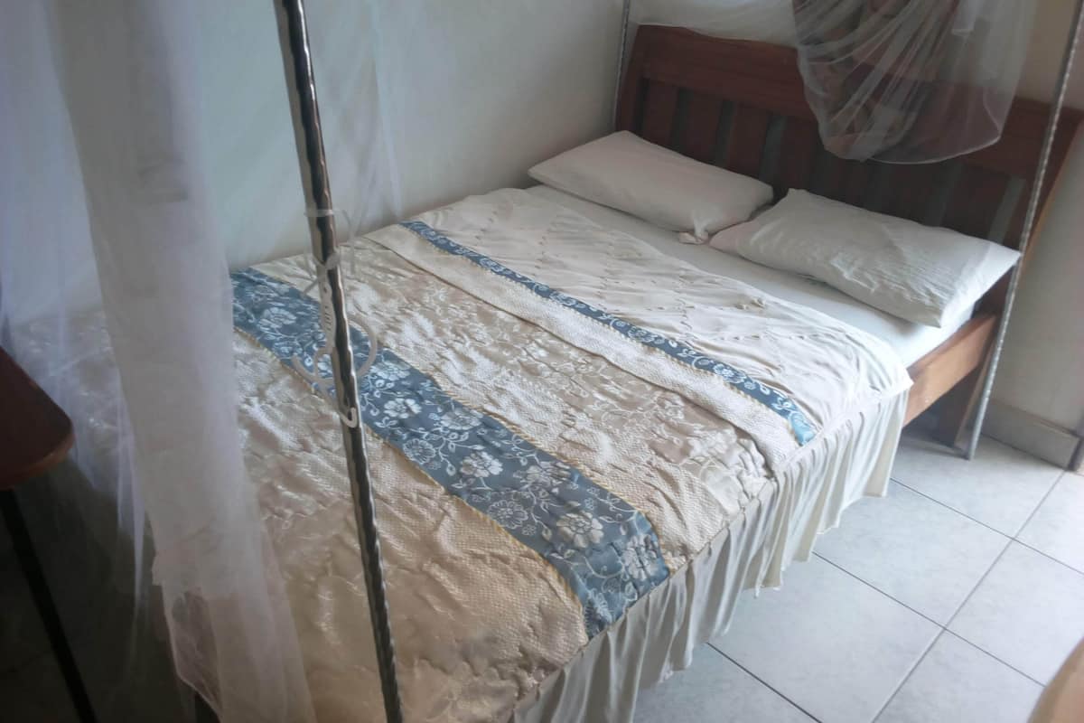 Un lit simple avec un baldaquin, une tête de lit en bois et une couvre-lit à motifs.