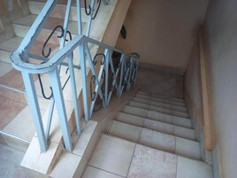 Uma escadaria com grades de metal e degraus cobertos de azulejos bege.