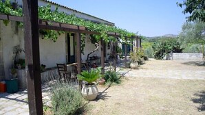 A covered patio area with a pergola, outdoor seating, and potted plants. - Il Bagolaro (Noto)