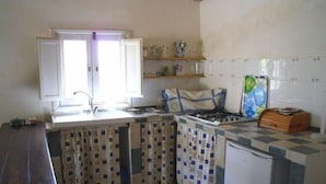 A compact kitchen with a window, a sink, a stove, and a refrigerator. - Il Bagolaro (Noto)