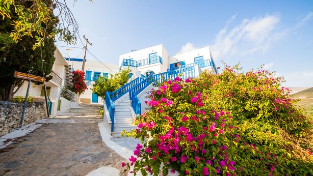 A white building with blue accents and a staircase leading to a balcony. - Hotel Saint George Valsamitis (Amorgos)