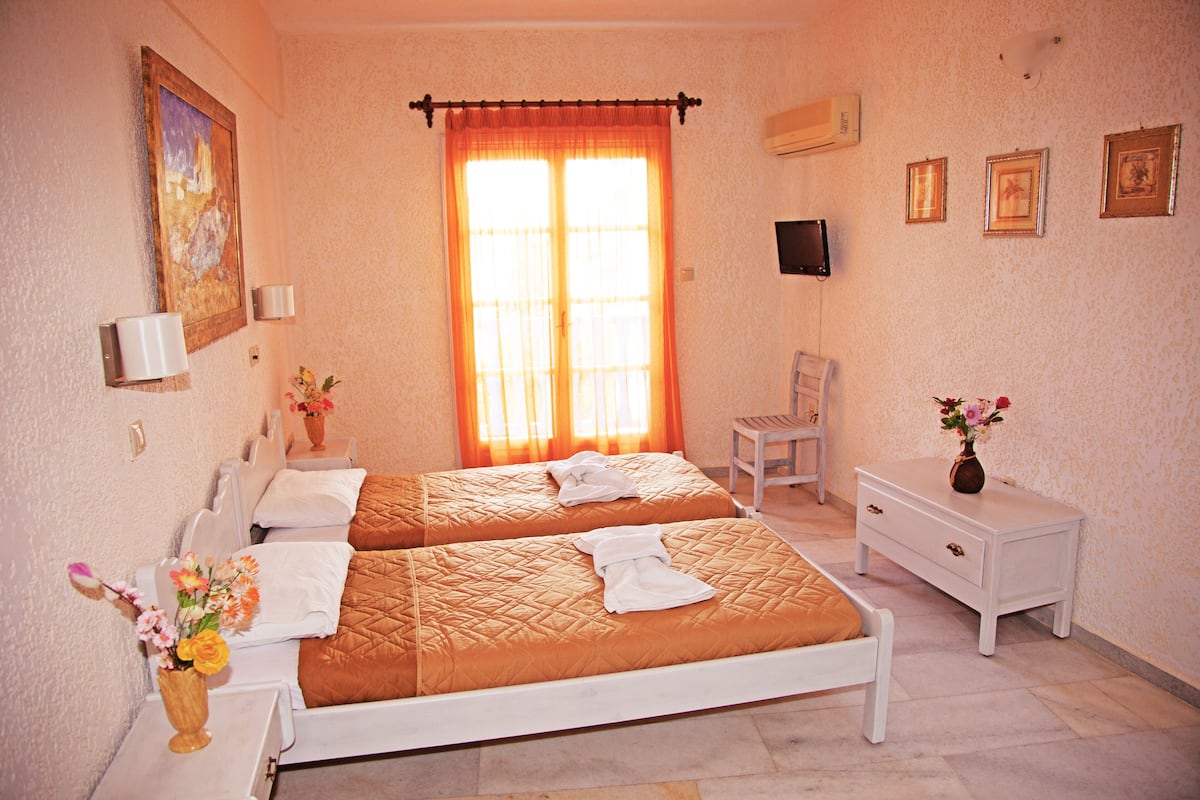 A hotel room with two beds, a white nightstand, a white dresser, a chair, a painting on the wall, and a window with curtains.