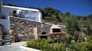 A stone building with a stone oven, steps, and a large pot. - Hotel Saint George Valsamitis (Amorgos)