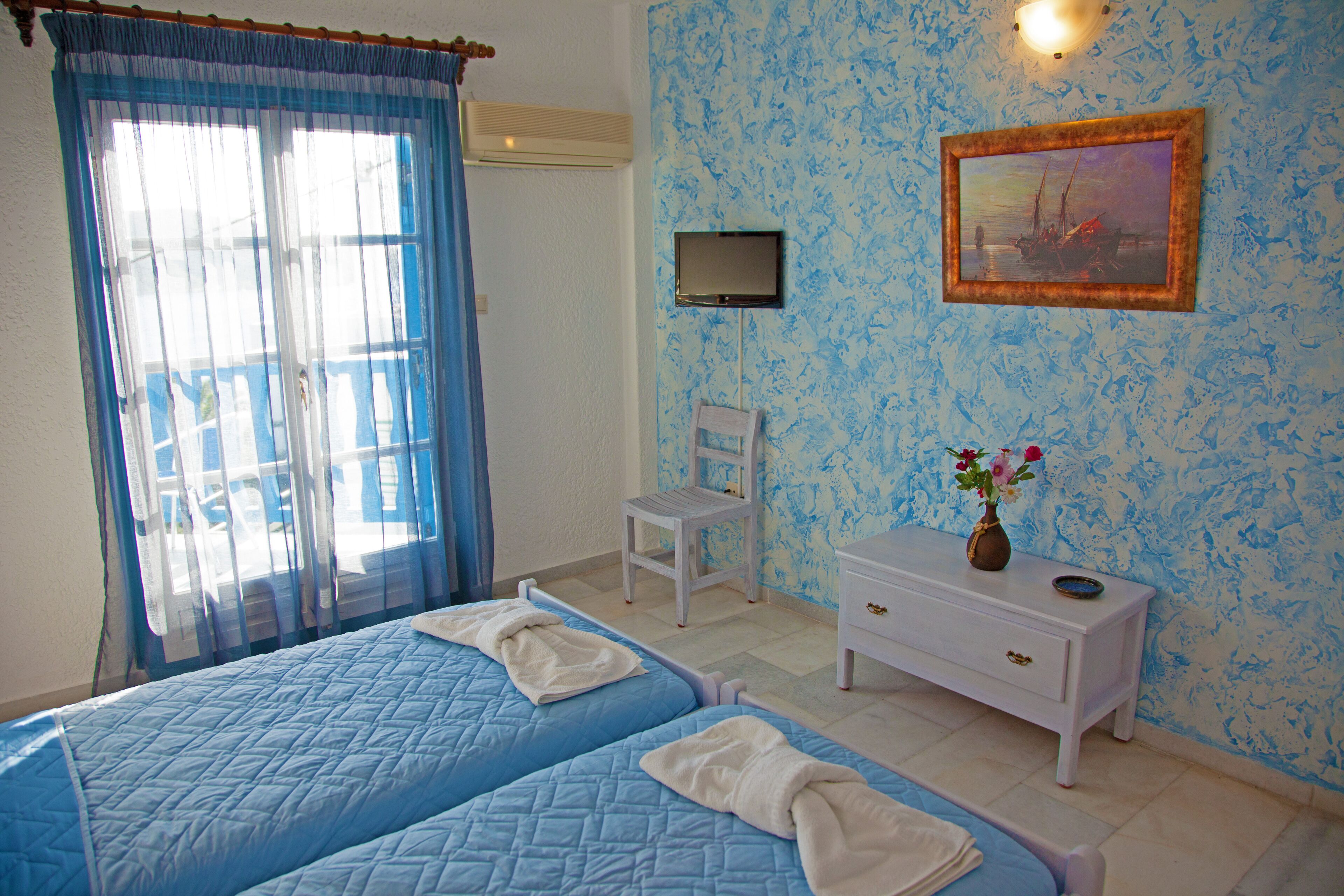 A hotel room with two beds, a TV, a chair, a nightstand, and a painting on the wall.