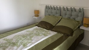 A bedroom with a bed, two bedside tables, and a headboard. - Functional holiday home 2 minutes from the beach (Ste anne)