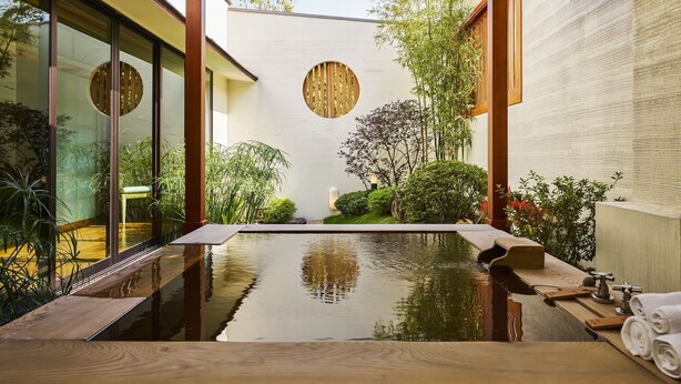 A serene indoor garden with a reflective water feature, wooden benches, and lush greenery. - Villa 32 (Taipei)