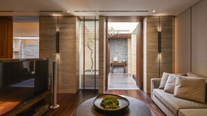 A modern living room with a flat-screen TV, a coffee table with a decorative bowl, and a sofa with cushions. - Villa 32 (Taipei)