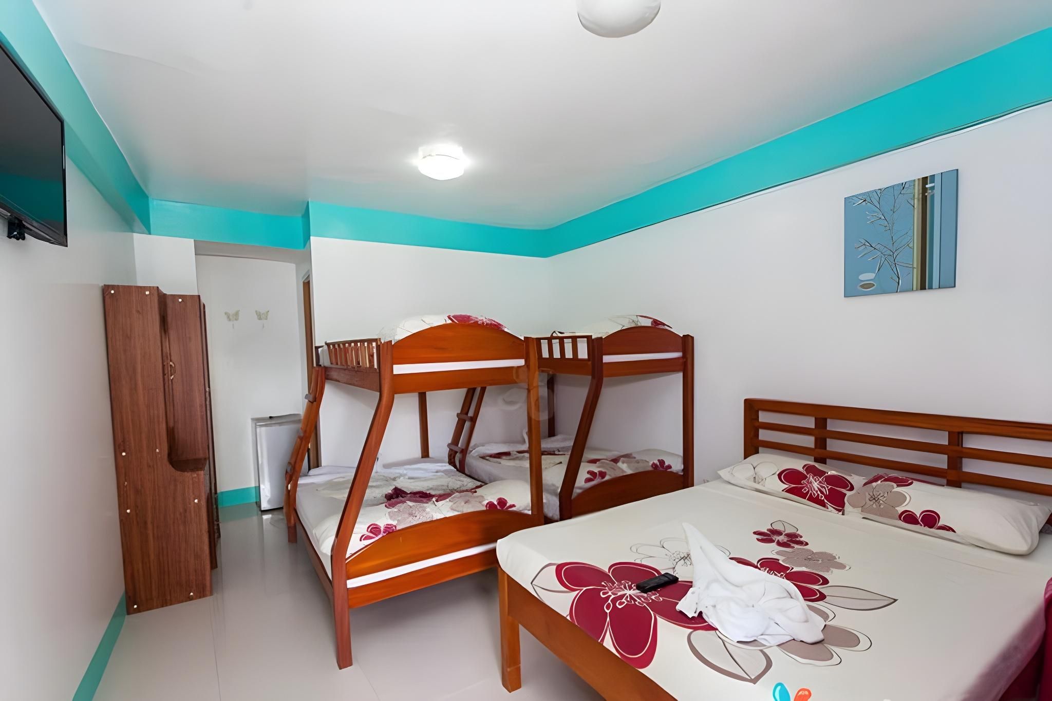 Un dormitorio con literas y una cama individual, paredes blancas y una pared de acento color turquesa.
