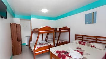 Un dormitorio con literas y una cama individual, paredes blancas y una pared de acento color turquesa.
