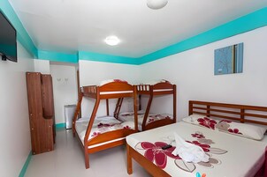 A bedroom with bunk beds and a single bed, white walls, and a teal accent wall.