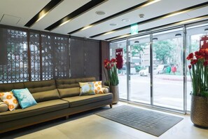 A reception area with a sofa, a large window, and a decorative screen. - Huada Hotel (Taipei)