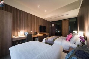 A hotel room with two beds, a desk with a computer, a TV, and a wardrobe. - Huada Hotel (Taipei)