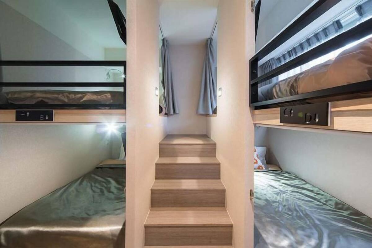 A compact, modern room with bunk beds, a central staircase, and built-in storage.