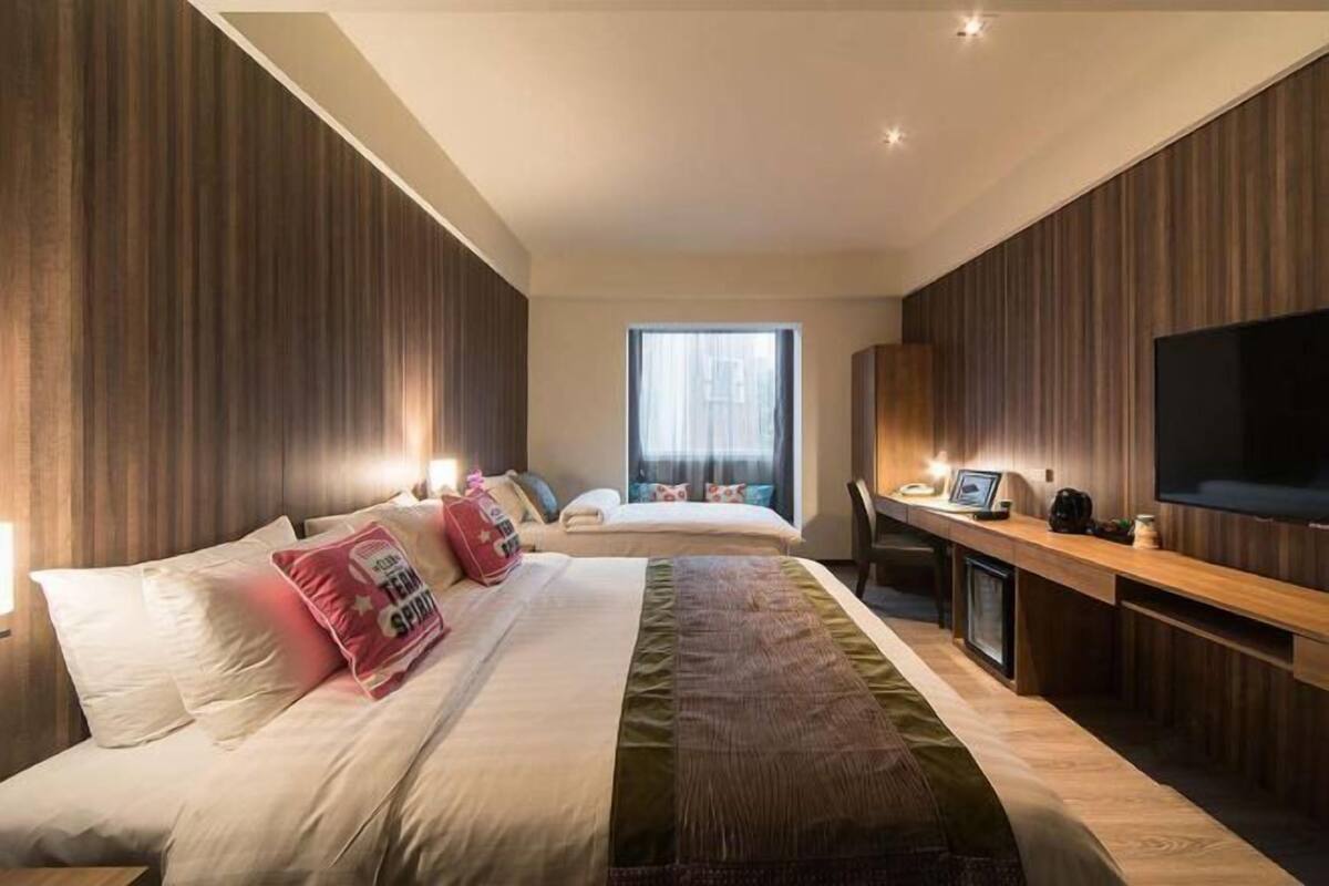 A modern hotel room with a large bed, a desk, and a TV.