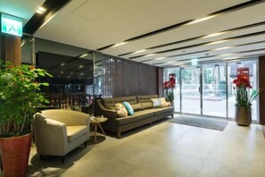 A modern lobby with a sofa, a coffee table, and a potted plant. - Huada Hotel (Taipei)