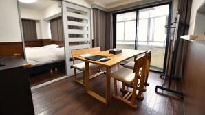 A hotel room with a bed, a wooden table with chairs, a desk, and a large window with curtains. - Randor Residence Tokyo Classic (Tokyo)