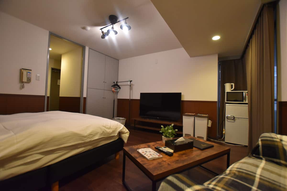 A hotel room with a bed, a television, a small kitchenette, and a coffee machine.