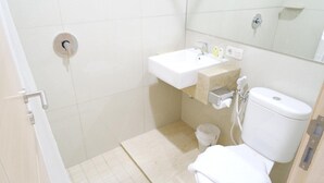 A small bathroom with a toilet, sink, and shower. - Yokotel Hotel (Bandung)