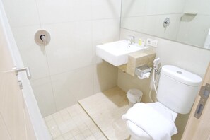 A small bathroom with a toilet, sink, and shower. - Yokotel Hotel (Bandung)