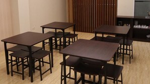 A room with multiple tables and chairs, a wooden partition, and a sign on the wall. - Yokotel Hotel (Bandung)