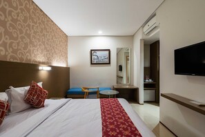 A hotel room with a bed, a desk, a chair, a television, and a mirror. - Yokotel Hotel (Bandung)