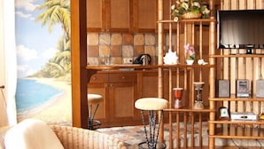 A room with a wooden ceiling, a wicker chair, a TV on a wall, and a kitchen area with a stone backsplash. - Sonya Hotel (Kyiv)