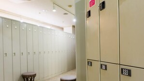 Eine Reihe von Schließfächern mit den Nummern 86, 87 und 88 sowie zwei Hocker in einem Flur.