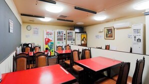 Ein Restaurant mit roten Tischen und Stühlen, einer Uhr an der Wand und Verkaufsautomaten.