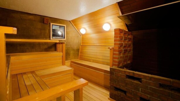 Ein Sauna-Raum mit Holzbänken und einem Kamin aus Backsteinen.