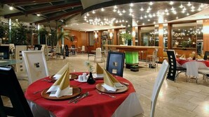 A restaurant with round tables set for dining, a bar area, and large windows allowing natural light. - Dukla Presov (Prešov)