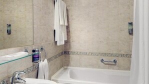 A bathroom with a bathtub, a glass shelf with toiletries, and a towel rack. - Dukla Presov (Prešov)