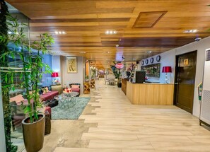 A hotel lobby with a reception desk, seating area, and potted plants. - Uncle Tom's Cabin Hotel (Cebu City)