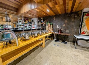 Montaje de bufé con platos de acero inoxidable, una mesa de madera y un fondo de pared de piedra.