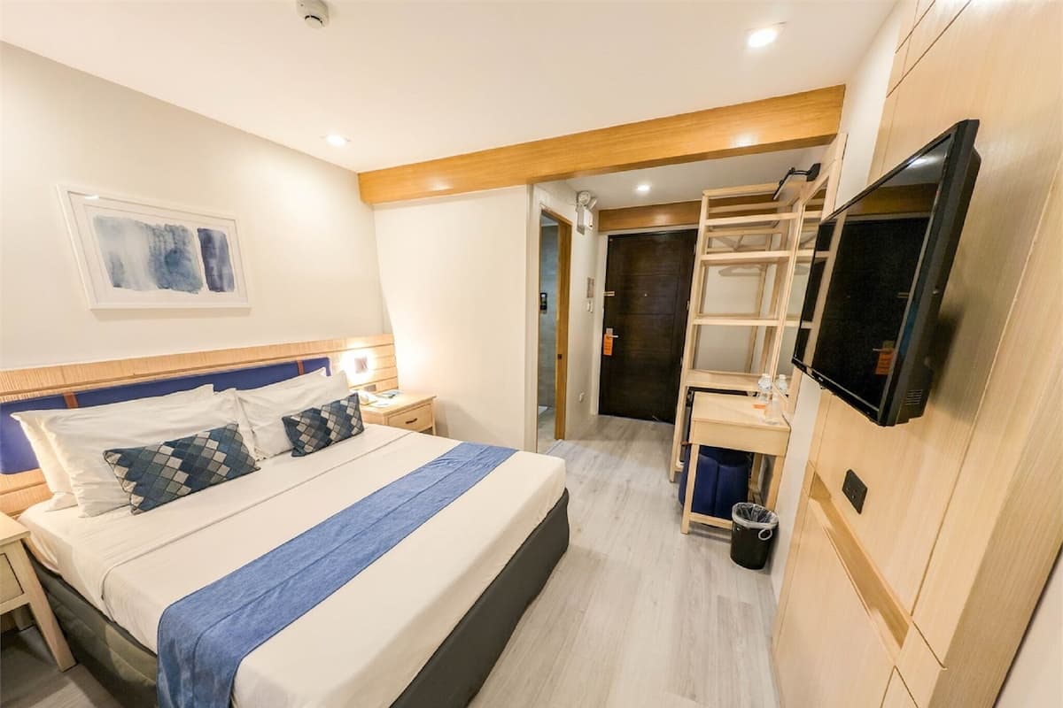 Une chambre d’hôtel comprenant un lit, des tables de chevet, une télévision, un bureau et une chaise.