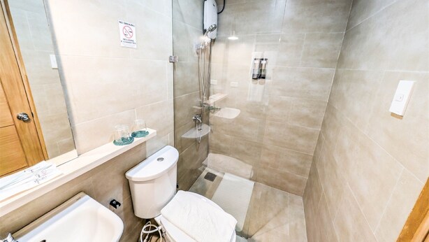 Un baño moderno con ducha acristalada, inodoro y lavamanos.