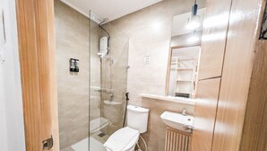 A modern bathroom with a glass shower enclosure, a toilet, a sink, and a mirror. - Uncle Tom's Cabin Hotel (Cebu City)