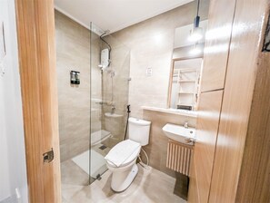 A modern bathroom with a glass shower enclosure, a toilet, a sink, and a mirror. - Uncle Tom's Cabin Hotel (Cebu City)