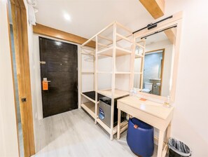 A room with a wooden door, a mirror, a desk, a blue trash bin, and a black trash bag. - Uncle Tom's Cabin Hotel (Cebu City)