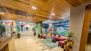 A hotel lobby with wooden flooring, red seating, and potted plants. - Uncle Tom's Cabin Hotel (Cebu City)