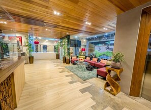 A hotel lobby with wooden flooring, red seating, and potted plants. - Uncle Tom's Cabin Hotel (Cebu City)